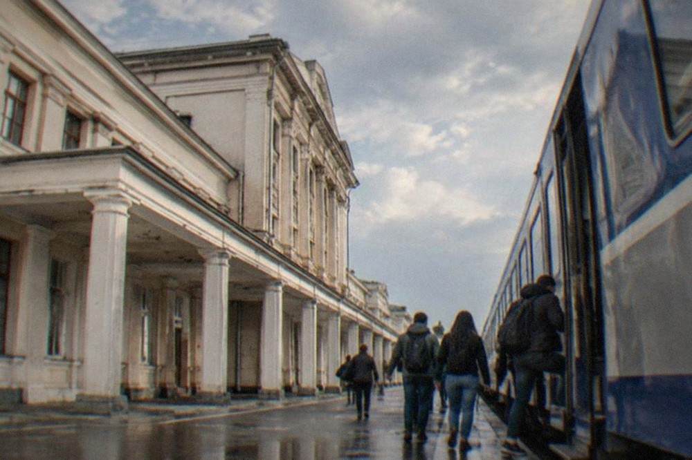 Passengers boarding a blue and grey passenger train at a platform in a Romanian railway station