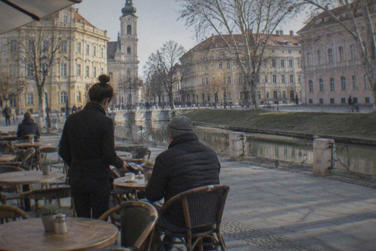A cafe terrace in a central square in Timisoara with a customer paying at a small table