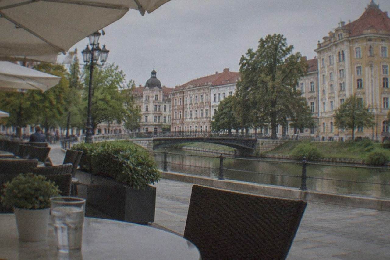 A table outside a restaurant in a historic square in Timisoara, with chairs, umbrellas and old buildings in the background