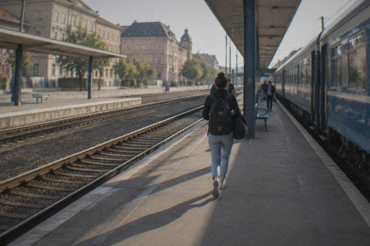 Two railway platforms at a Romanian train station with a blue intercity train waiting beside the platform