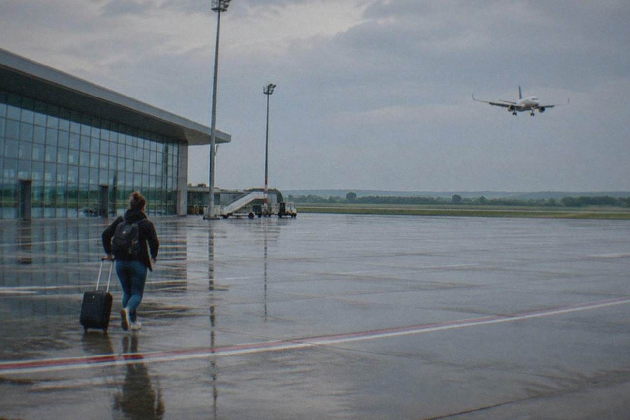 A passenger aircraft descending over the runway at Timisoara Traian Vuia Airport with open fields beyond