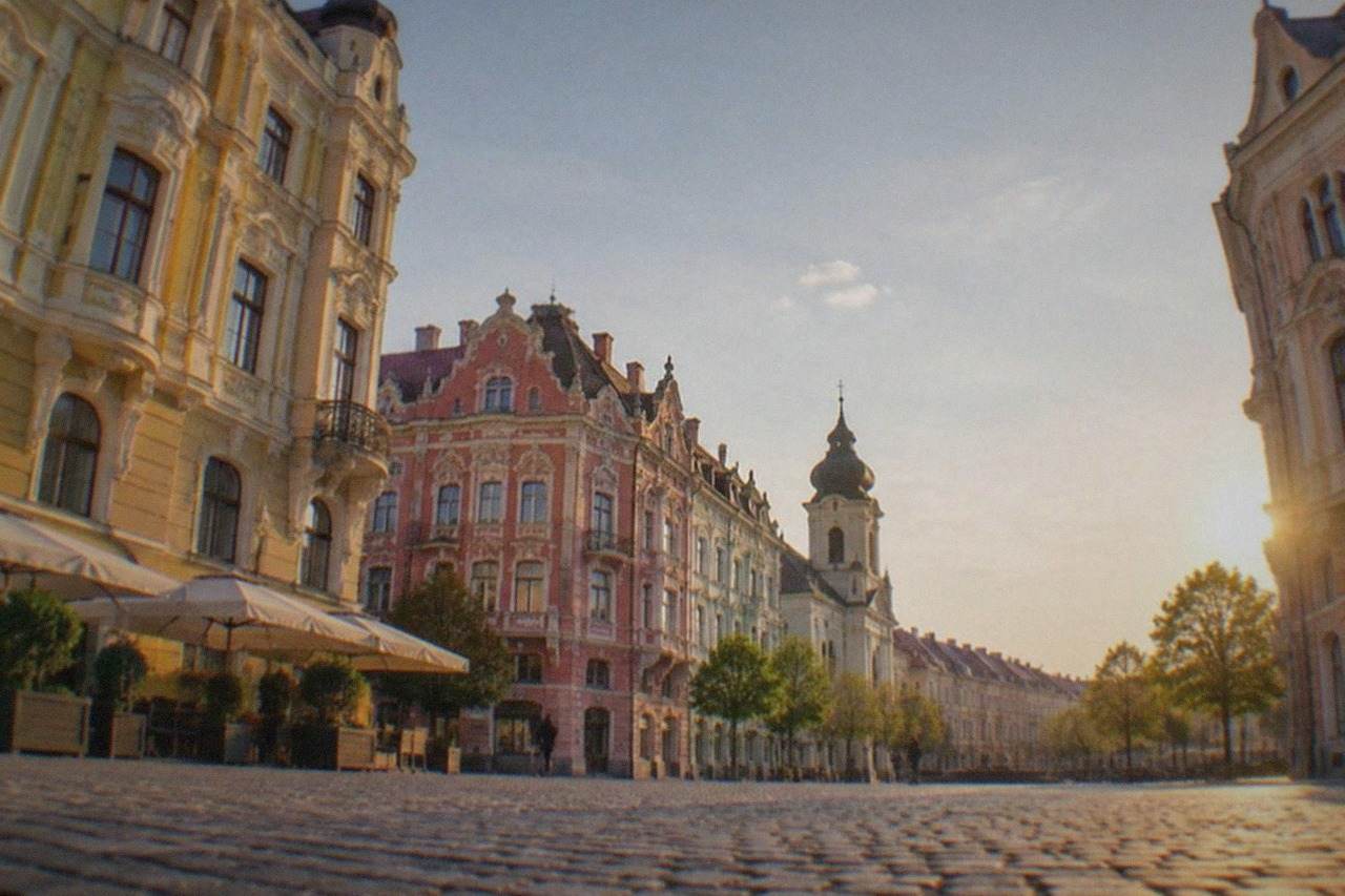 Colorful baroque facades around a wide square in Timisoara's old town at golden hour