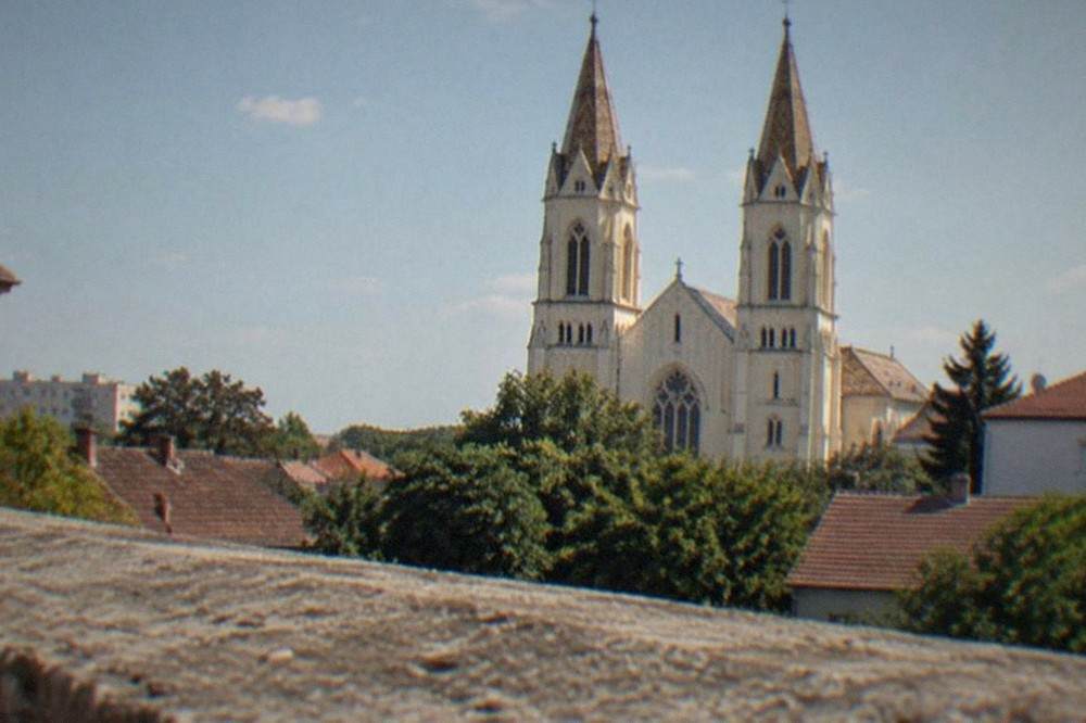 The twin neo-Gothic towers of the Millennium Church rising over low residential rooftops in Elisabetin