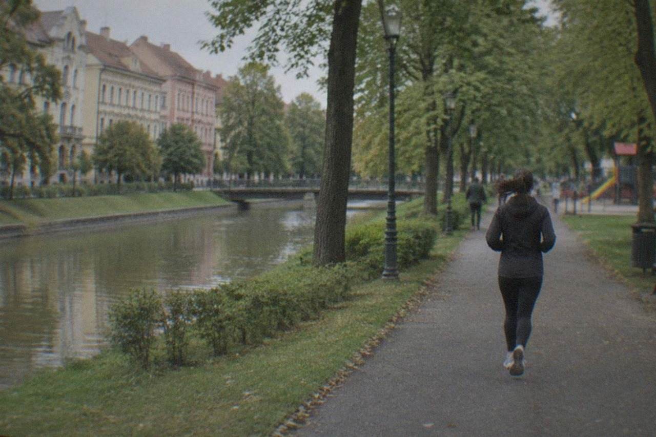 A tree-lined park path in central Timisoara with a children's playground in the distance
