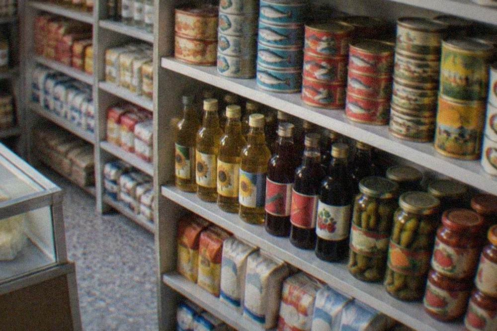 Close-up of shelves stacked with retro Romanian food tins, bottles and grocery packaging