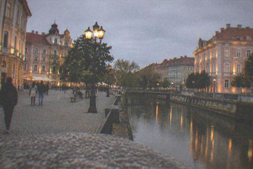 A street corner in Timisoara at dusk with lit facades and pedestrians