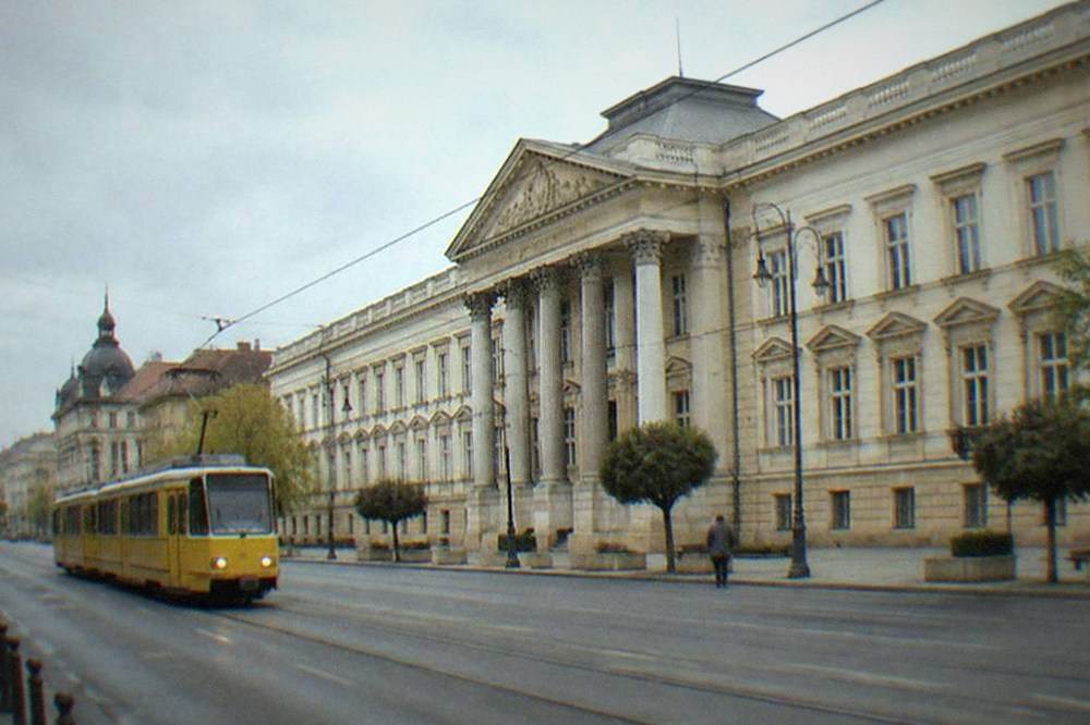 Yellow tram traveling along a boulevard lined with historic buildings in an old city district