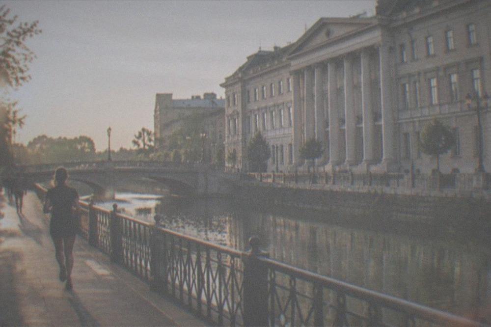 Riverside promenade along a canal with historic bridges and people strolling