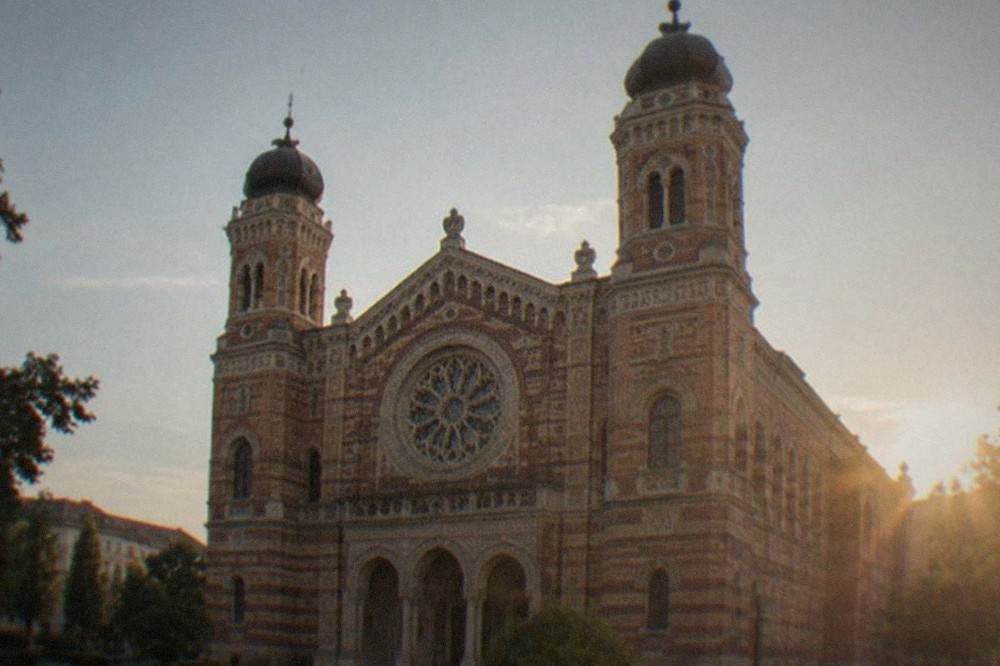 Detail of the synagogue's patterned brickwork and arched windows under afternoon light