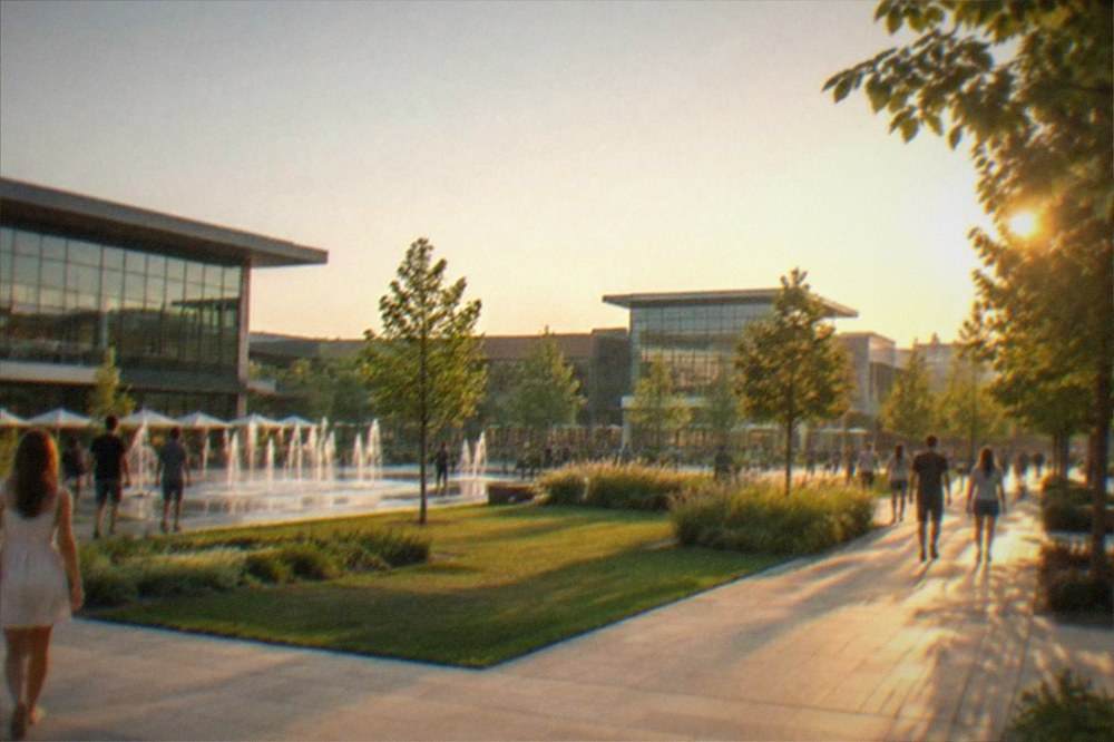 Park lawns and walkways between modern buildings with people strolling in summer light