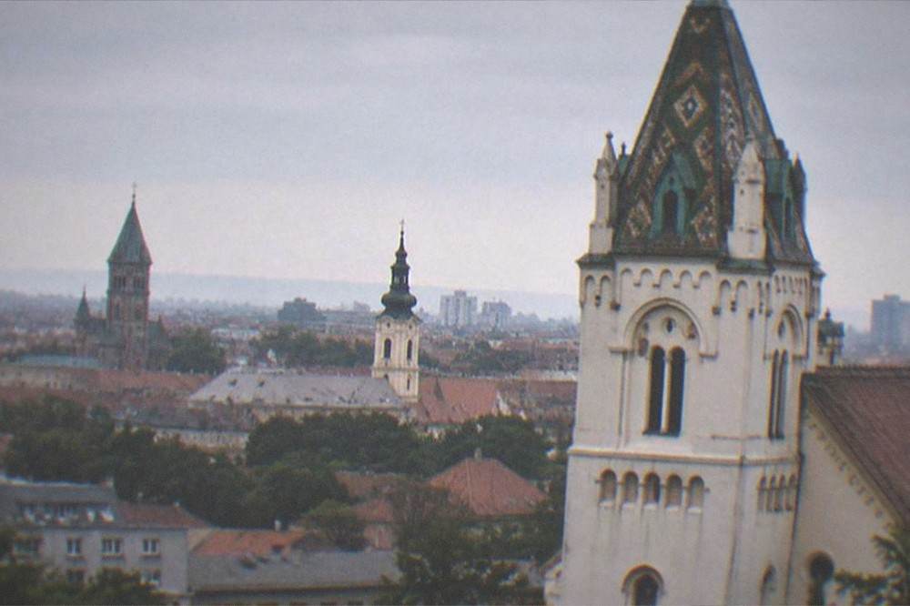 A city skyline at dusk with church towers and rooftops seen from a distance