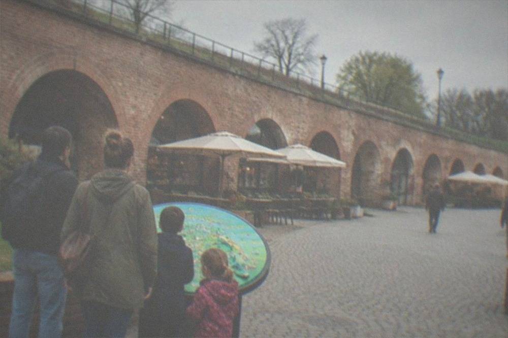 A family looking at a colorful interactive exhibit inside a brick-vaulted museum space