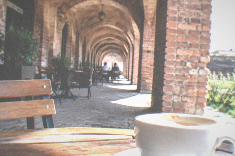 A coffee cup on a table under the brick arches of the bastion corridor