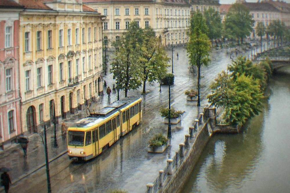 Yellow tram passing colorful baroque buildings on a Timisoara street