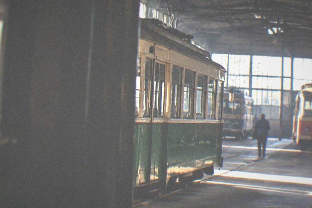 A vintage tram passing historic buildings on a city street