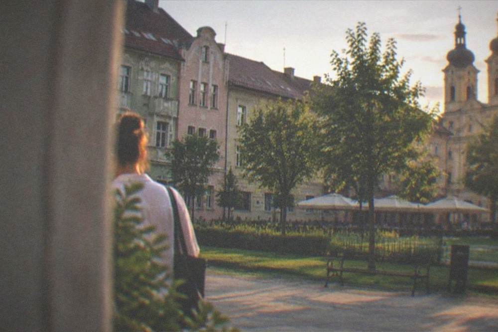 Illuminated historic square at dusk with cafe terraces and lit church towers