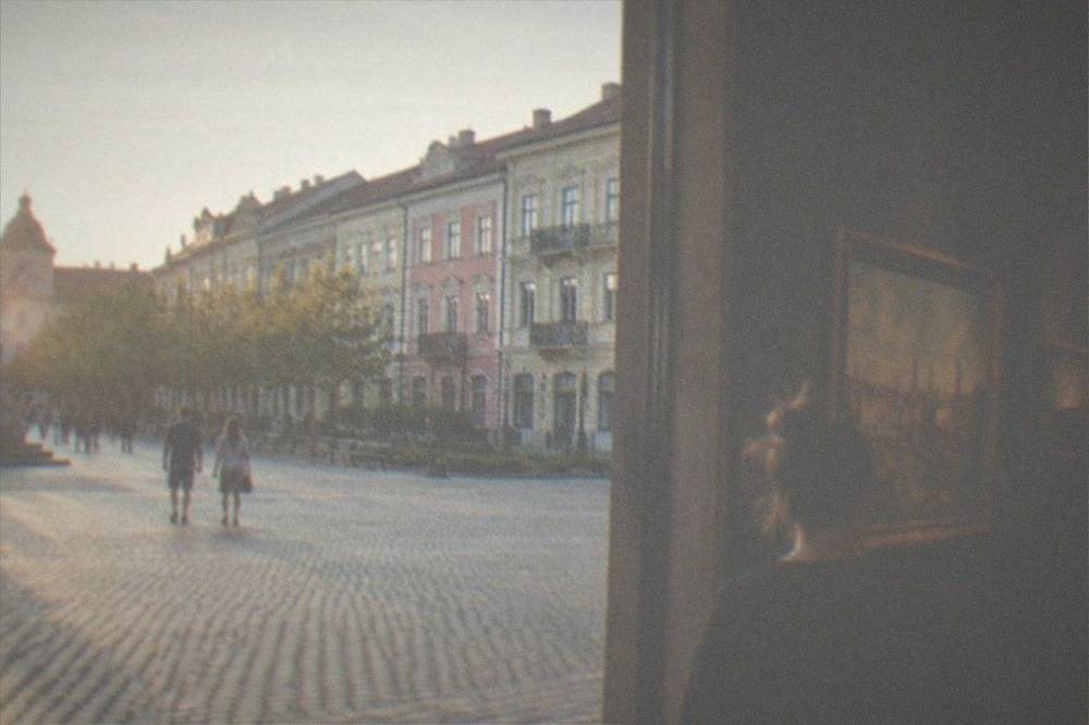 Visitors walking through a museum gallery with framed paintings on dark walls