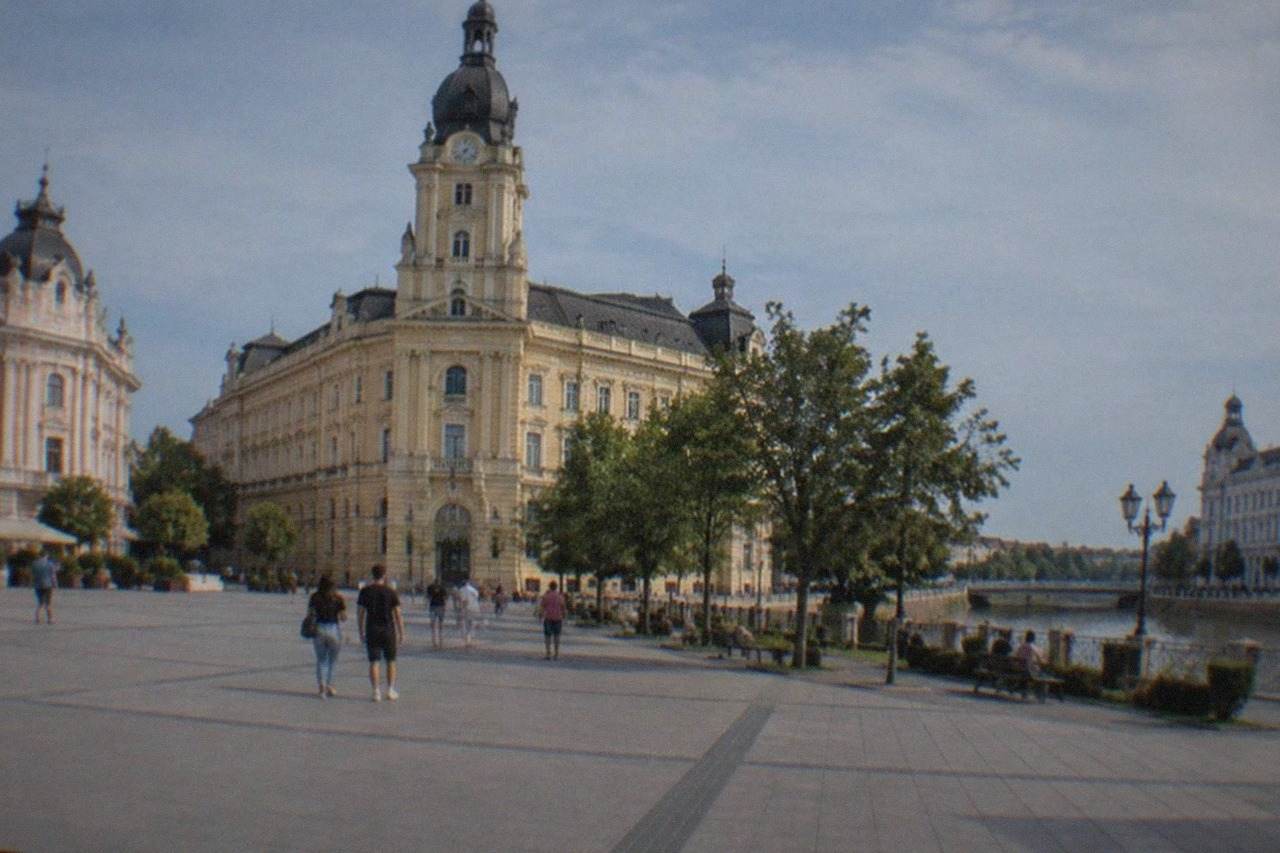 A wide city square in Arad with historic buildings and people walking on a sunny day