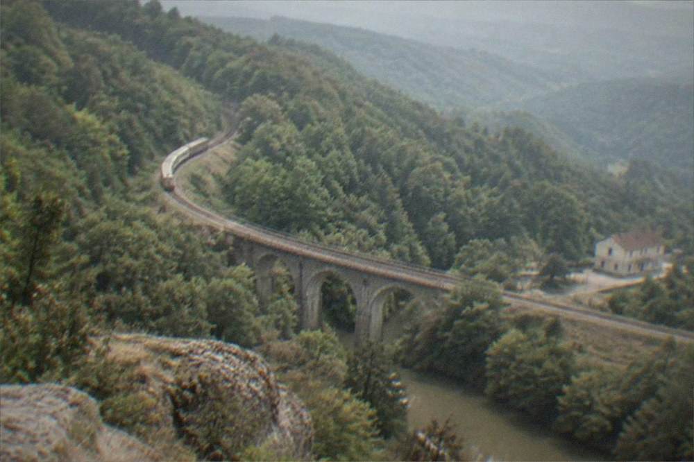 A mountain viewpoint over rolling forested hills stretching to the horizon in western Romania
