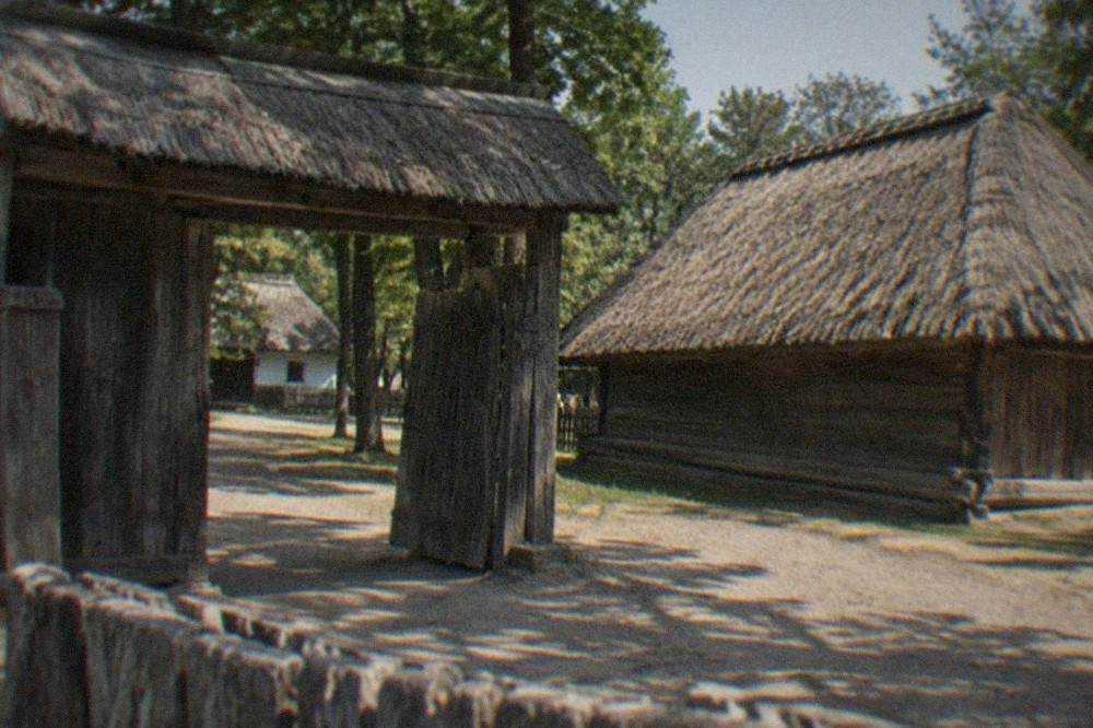Traditional wooden gate and thatched barn in a Banat village museum setting
