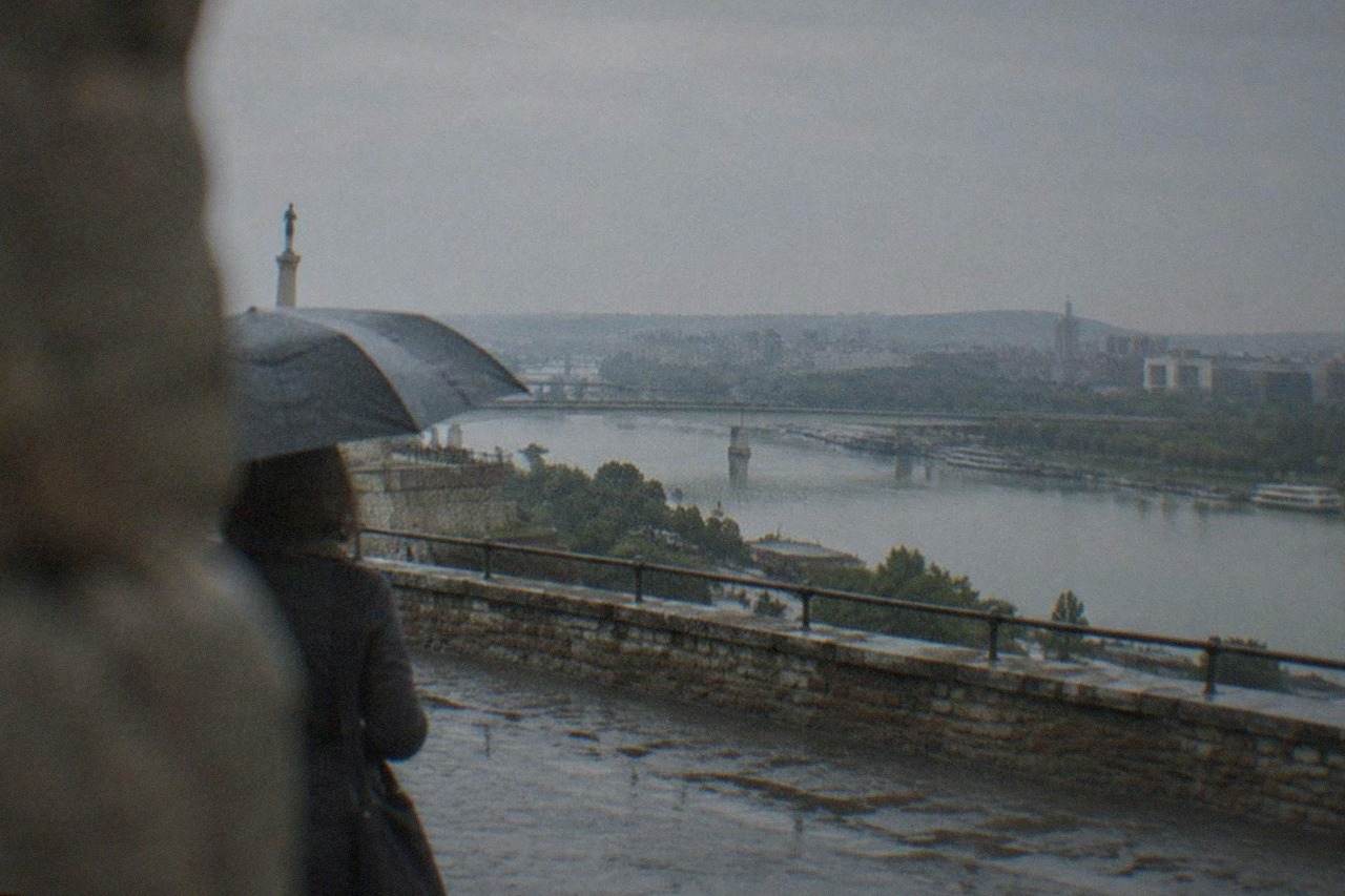 View over a wide river crossing a city with bridges and low hills in the distance