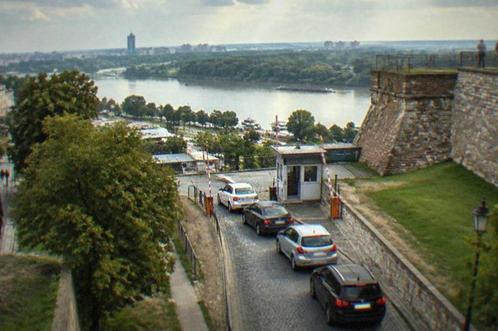 Queue of cars waiting at a small border post with striped barrier arms