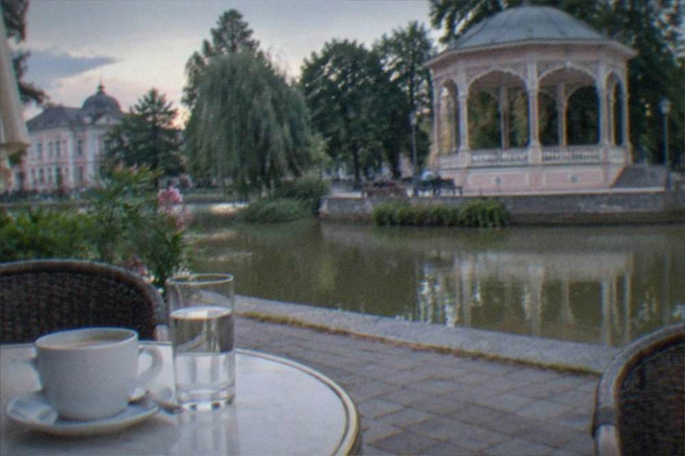 A café table with a cup of coffee and a glass of mineral water on a sunny terrace