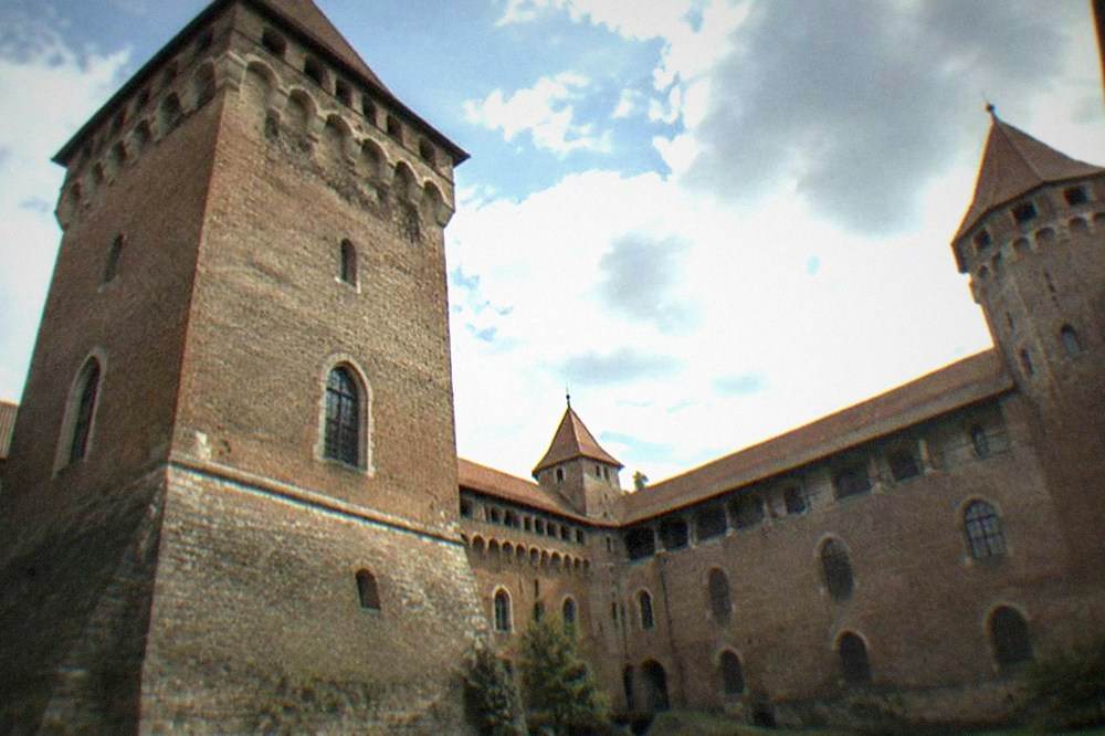A medieval castle courtyard enclosed by high stone walls with arched windows
