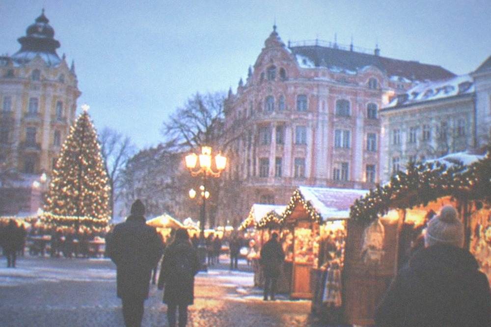 A festive Christmas market with wooden stalls and lights in a large city square