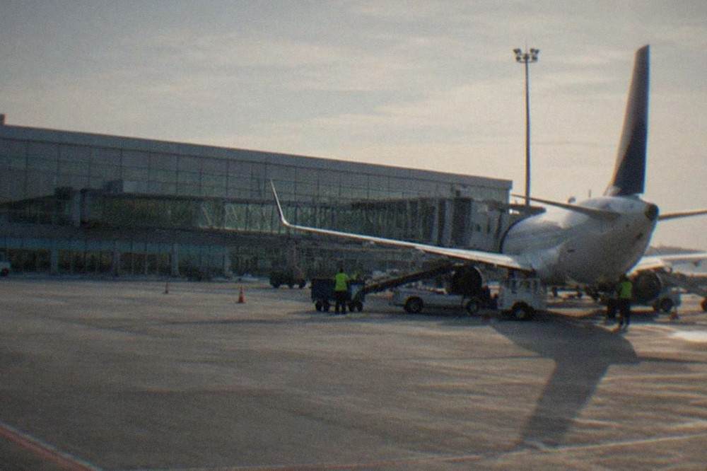 A low-cost airliner parked at a gate with ground crew working around the wing