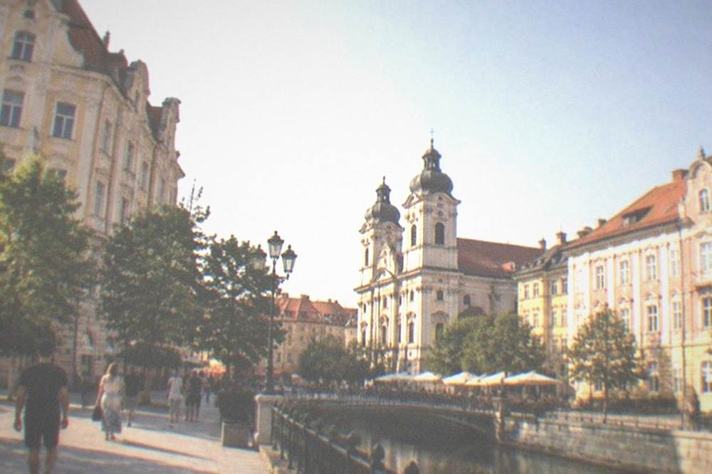 People strolling through a lively Timisoara square in the early evening