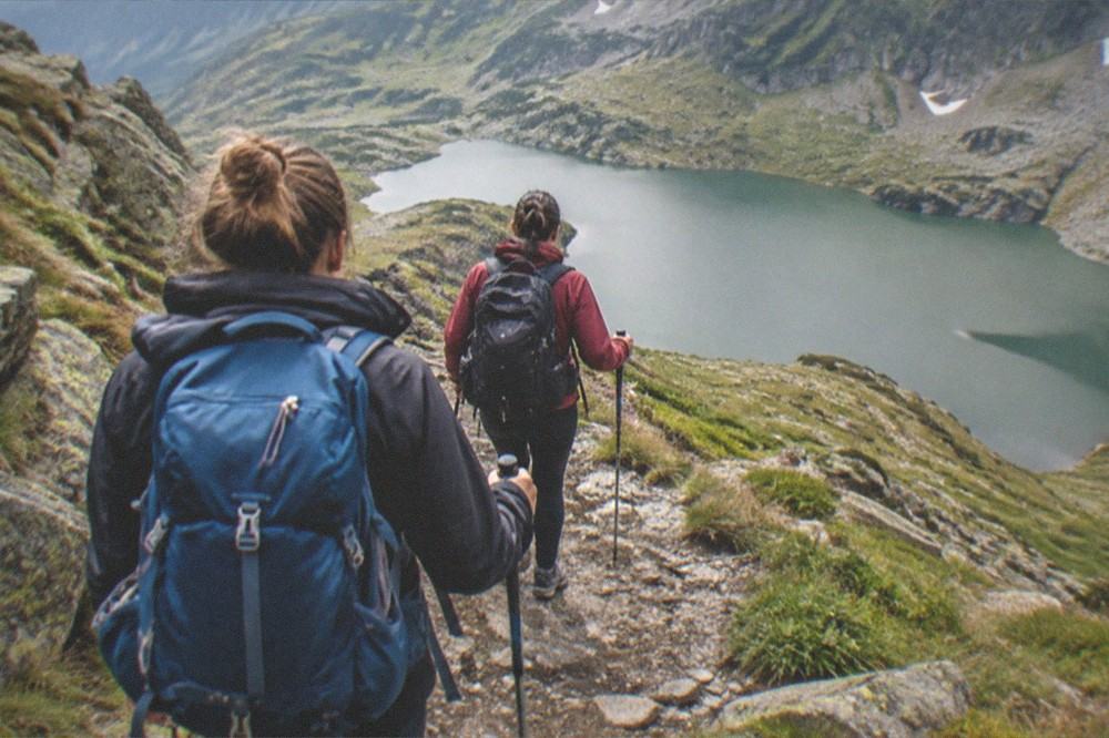 Hikers on a mountain trail above a glacial lake in a national park