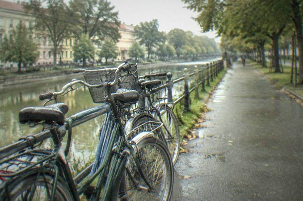Bicycles parked on a promenade beside a canal with historic buildings in the background