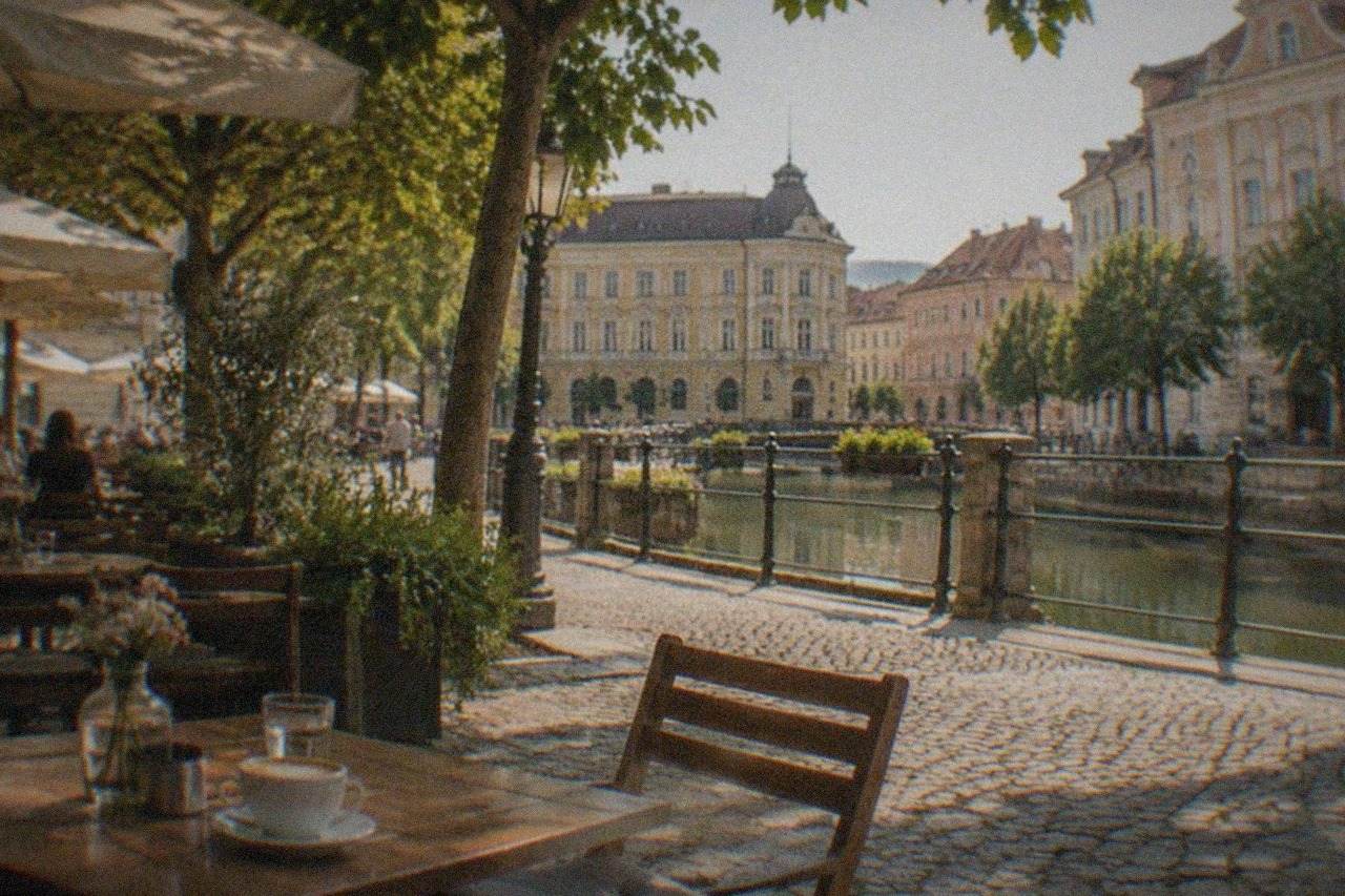 A sunny cafe terrace on a pedestrian square in Timisoara with small tables, coffee cups and historic facades