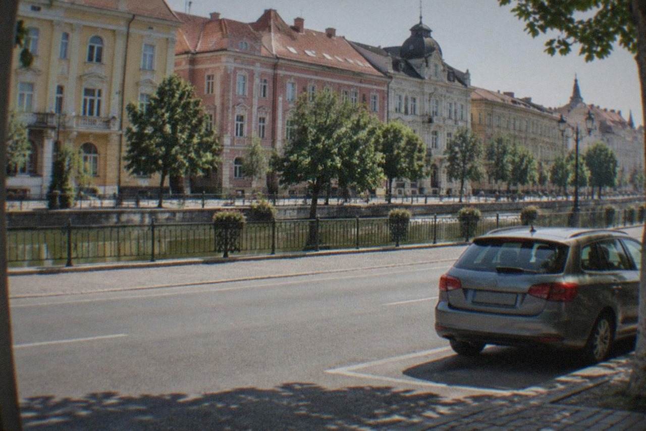 A rental car parked on a wide boulevard lined with colorful historic buildings in central Timisoara