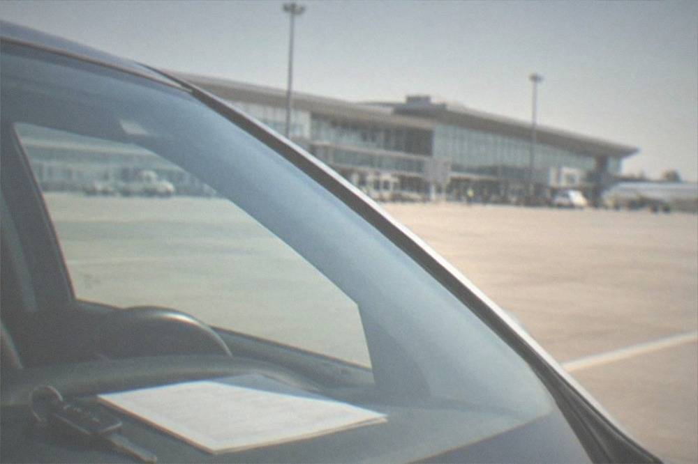 A car key and rental agreement on the dashboard of a small car seen through the windshield