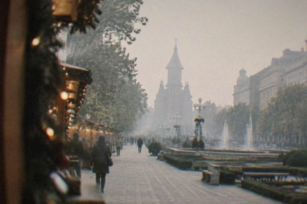 Wooden market stalls with garlands and warm lights along a European square at night