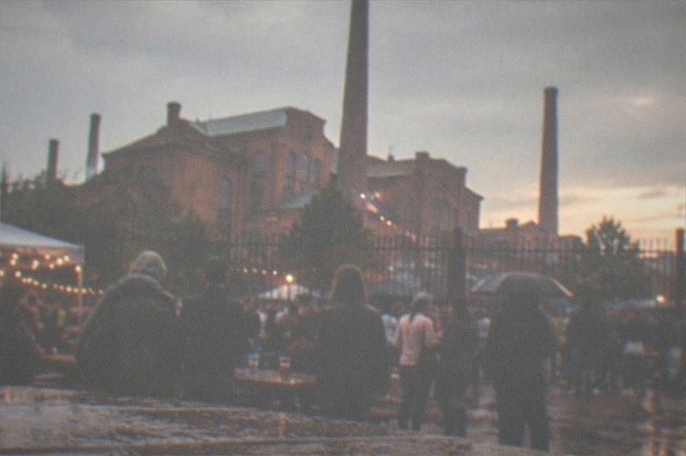 Crowd at an outdoor festival with drinks at dusk