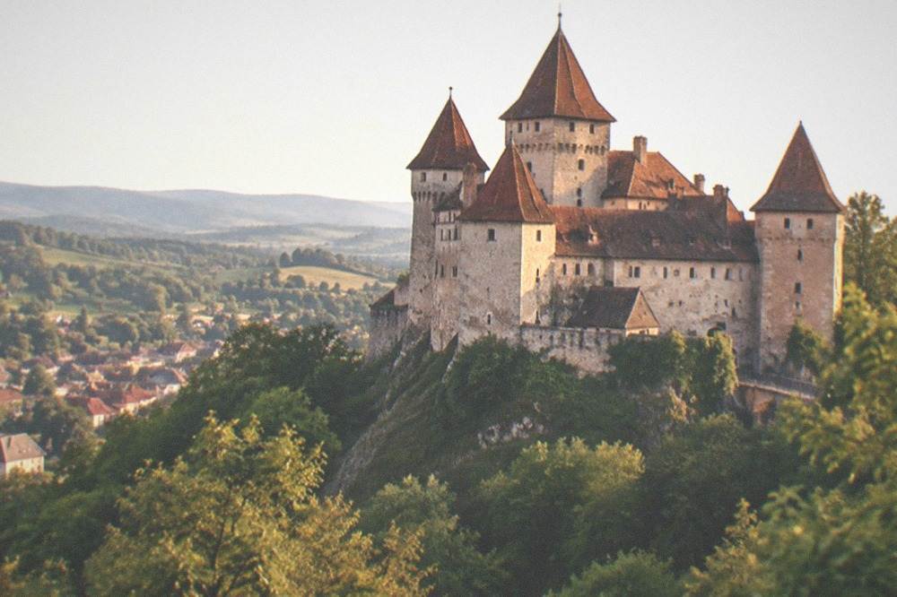 Medieval castle towers above a green valley on a day trip from Timisoara