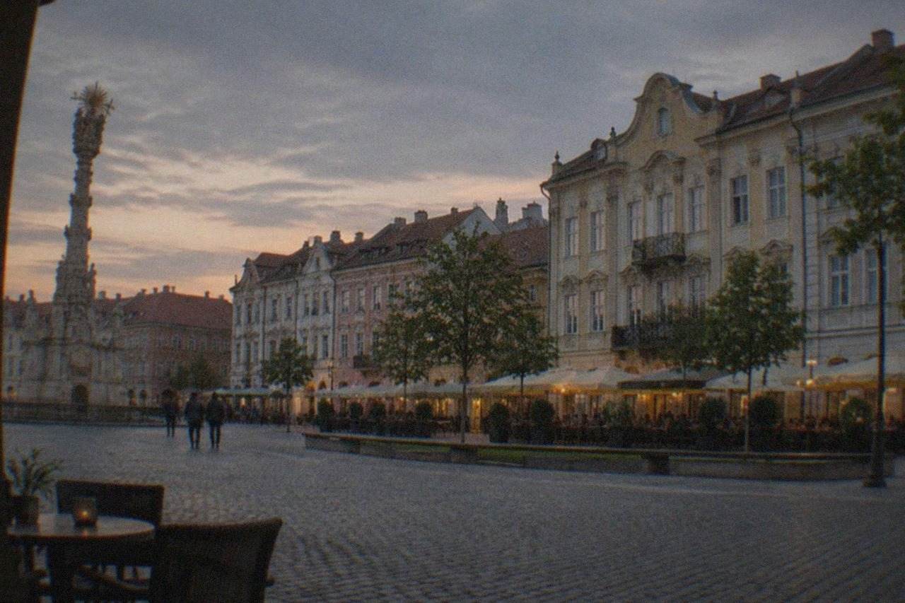 Union Square in Timisoara at dusk with baroque buildings and cafe terraces