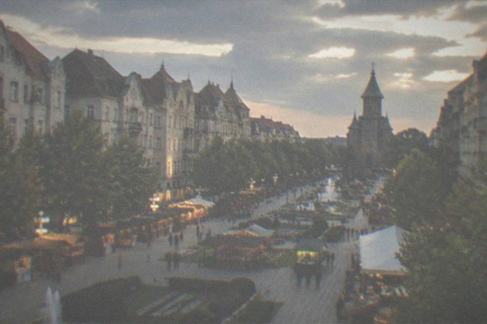 Wooden market stalls with festive lights in a city square at dusk