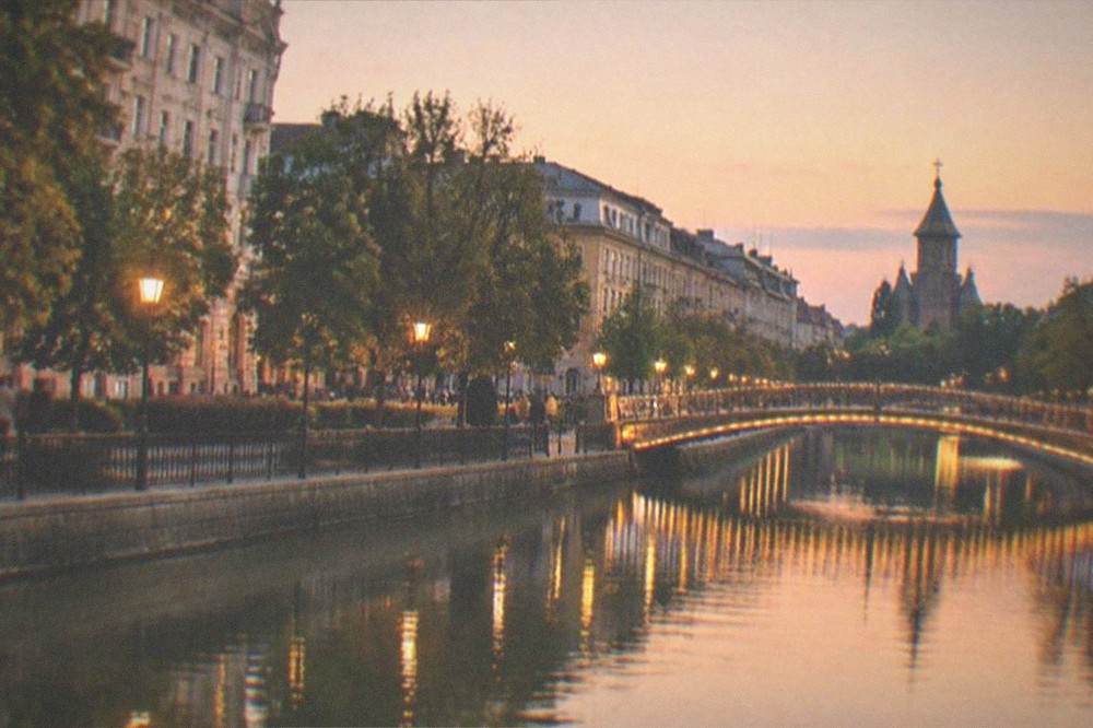 Evening view of a lit bridge over a city canal with reflections on the water