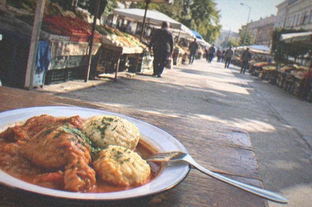 A plate of paprika chicken stew with dumplings and a fork on a rustic table