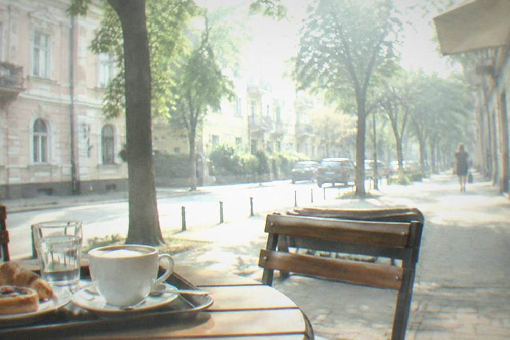 A tray of coffee and pastries on a cafe table in a sunlit Romanian cafe