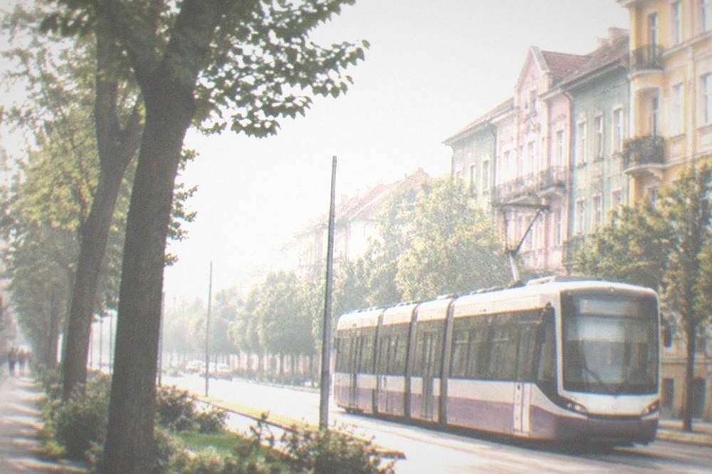 A modern tram passing colorful apartment buildings on a European boulevard