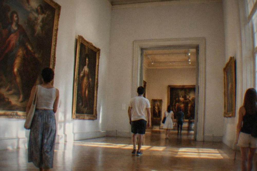 Visitors walking through a lit museum gallery of baroque paintings in Timisoara