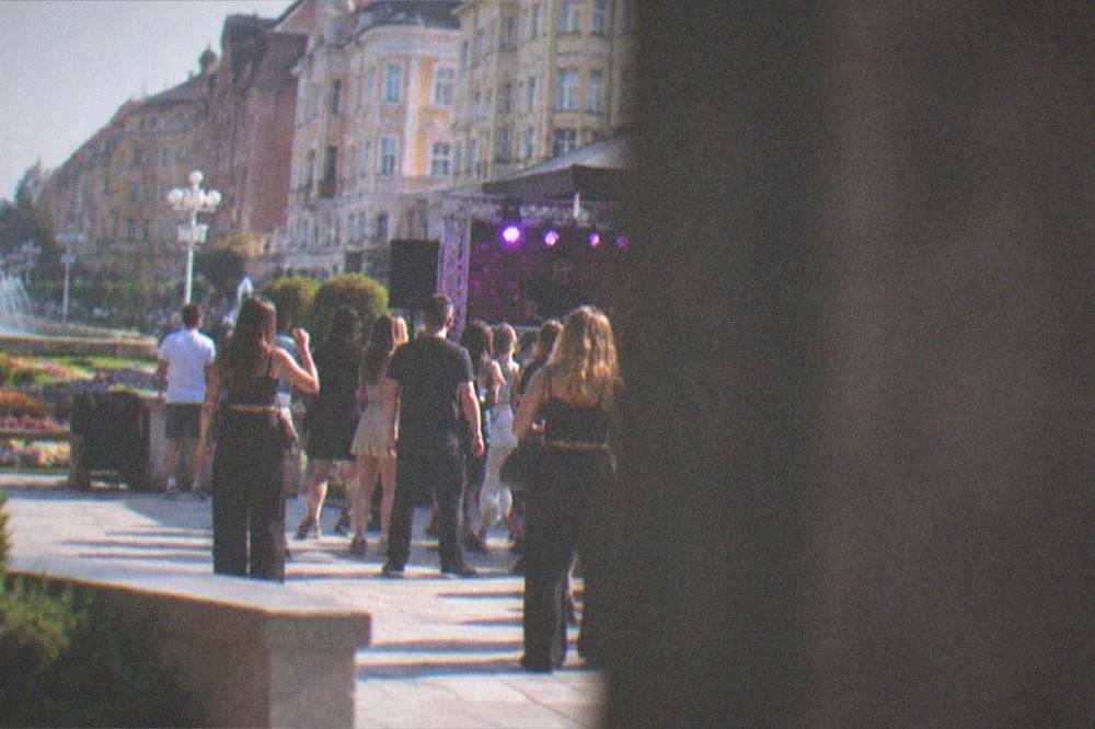 Crowd of people dancing in a club with a DJ booth and purple lighting