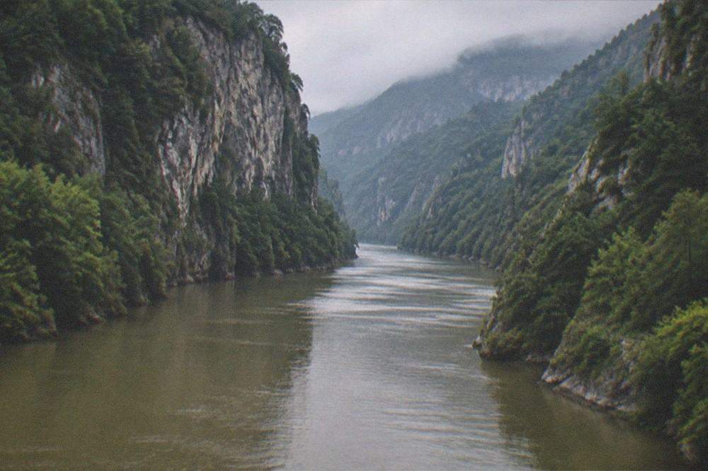 A river cutting between forested cliffs in a remote mountain gorge landscape