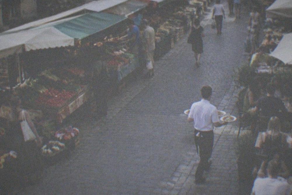 A waiter carrying plates to a table in a busy restaurant