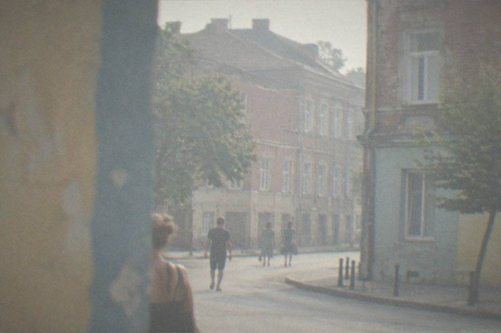 People walking past colorful painted walls in a city neighborhood with old buildings